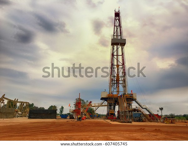 Oil and gas drilling rig onshore dessert with\
dramatic cloudscape