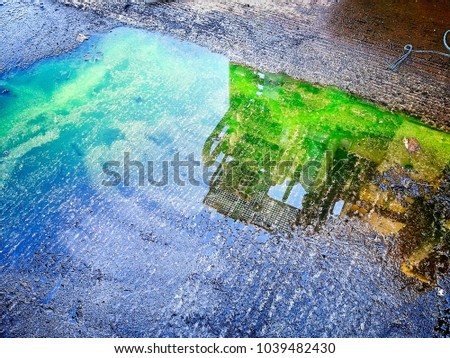 Oil and gas equipment reflected in the puddle. Very bright colors