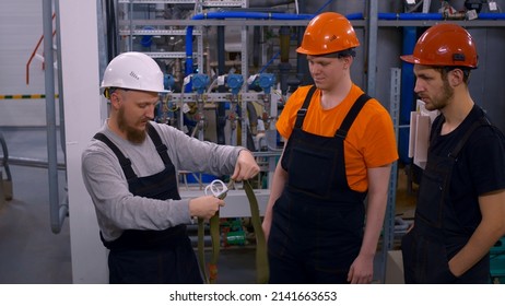 Oil And Gas Industry Operator At The Workplace. Safety Training At Work. Men In Helmets At The Workplace In The Workshop With Hazardous Chemicals Are Trained To Put On A Breathing Mask.