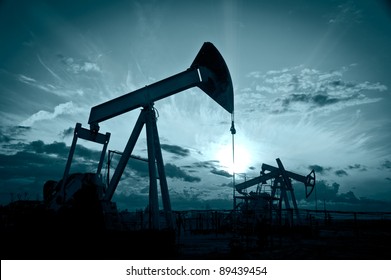 Oil and gas industry. Silhouette oil pumps on a sunset sky background. Toned.
