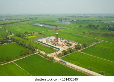 Oil And Gas Land Drilling Rig Onshore In The Middle Of A Rice Field Aerial View From A Drone