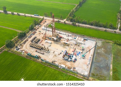 Oil and gas land drilling rig onshore in the middle of a rice field aerial view from a drone