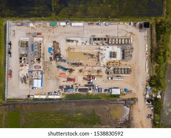 Oil And Gas A Land Rig, Onshore Drilling Rig, In The Middle Of A Rice Field Aerial View From A Drone