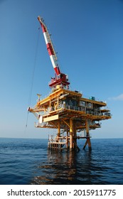 Oil and gas platform standing in the gulf or offshore and operation by technician. Crane moving any cargo or tools basket from supply boat to the platform. Heavy lift was moving by crane technician.