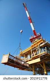 Oil And Gas Platform Standing In The Gulf Or Offshore And Operation By Technician. Crane Moving Any Cargo Or Tools Basket From Supply Boat To The Platform. Heavy Lift Was Moving By Crane Technician.