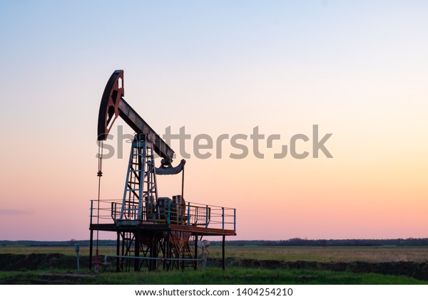 Oil and\
gas production equipment running at\
sunset
