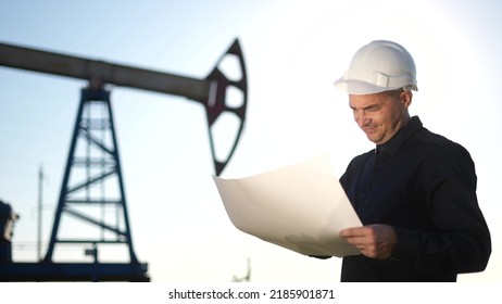 oil industry. engineer next to an oil rig with a paper plan. oil business production financing concept. gas production. a worker sun with a paper documents oil production near the station - Powered by Shutterstock