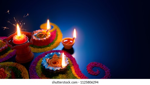 Oil lamps lit on colorful rangoli during diwali celebration - Shutterstock ID 1125806294