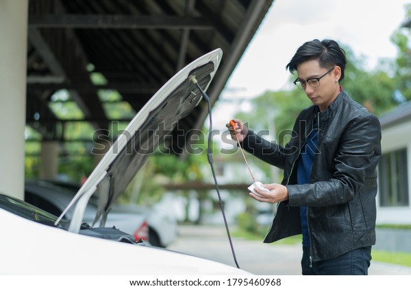 man checking oil\
level in a car, change oil\
car\
