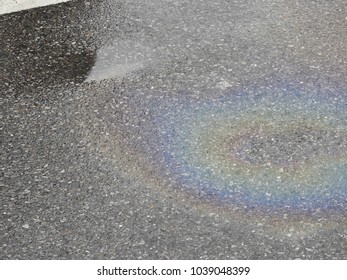 Oil On Water: Oil Leak On The Tarmac Surface Of A Wet Car Park