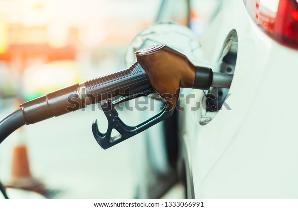 oil Petrol pump\
filling nozzles in Gas station in a service in color tone image\
with blur station\
background