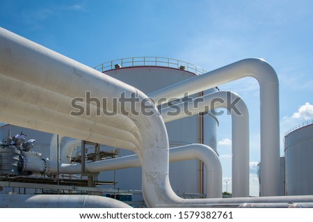 Oil pipeline and Oil storage tank farm in the petroleum refinery.Above ground storage tanks can be used to hold materials such as petroleum,waste matter, water,chemicals,and other hazardous materials.