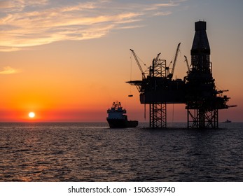 Oil Platform And A Supply Vessel In The North Sea During Sunset. 