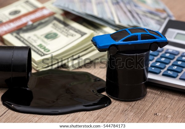 oil pool and barrels with dollars, calculator and\
toy car on the table.