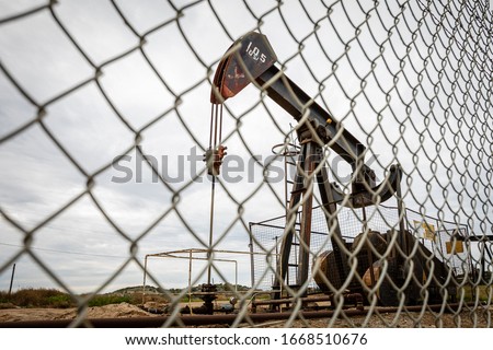 Oil Pump in Cloudy Rough Weather with Chain Link Fence
