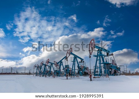 Oil pump jack under the blue sky with clouds winter working. Oil rig energy industrial machine for petroleum in the sunset background for design. Nodding donkey