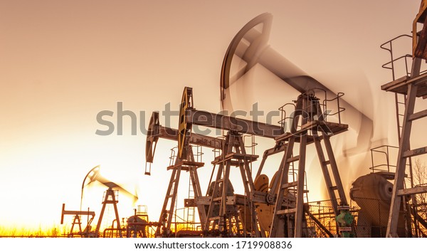 Oil pump rig. Oil and gas production. Oilfield\
site. Pump Jack are running. Drilling derricks for fossil fuels\
output and crude oil production. War on oil prices. Global\
coronavirus COVID 19\
crisis.