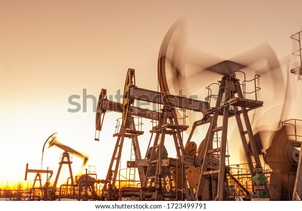 Oil pump rig. Oil and gas production. Oilfield\
site. Pump Jack are running. Drilling derricks for fossil fuels\
output and crude oil production. War on oil prices. Global\
coronavirus COVID 19\
crisis.