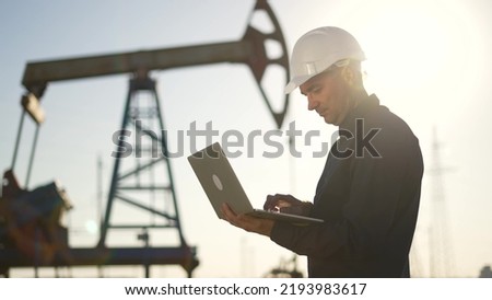 Oil pump.Engineer work with laptop and diagram.Checking operation of oil pump at plant.Silhouette of man in an industrial area.Silhouette of an engineer checking operation of an oil pump in desert Stock fotó © 