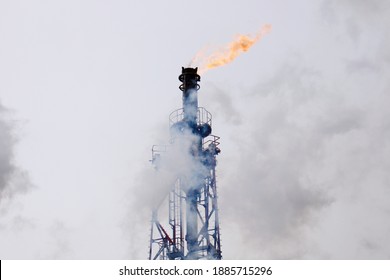 Oil refinery plant flare stack. Flames can be seen from the top of the tower.