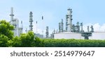 Oil refinery plant from industry zone with lush green trees and blue sky, large Oil and gas petrochemical industrial, Refinery factory oil storage tank and pipeline, Ecosystem and good environment.