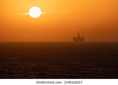 An Oil Rig Passes Under A Sunset In The Gulf Of Mexico