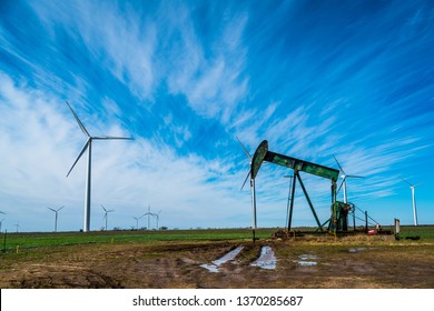 Oil Rig Pumping Oil In West Texas With Huge Wind Farm Creating Renewable Energy In Background