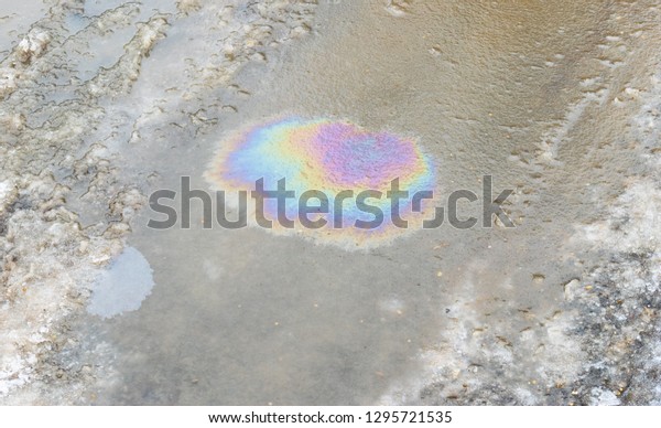 Oil slick on water in winter. The use of\
chemical reagents on the roads in the winter. Water pollution with\
oil and fuel spilling, oil industry.\
