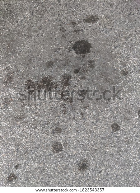 Oil stains on concrete in a\
parking lot useful texture and background pavement and black\
blotches