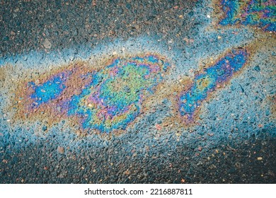 Oil stains on wet asphalt. Puddles are contaminated with multicolored streams of oil. - Shutterstock ID 2216887811