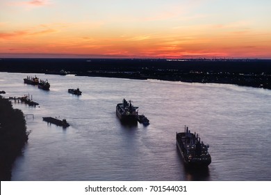 Oil Tanker Ships Form A Line Along The Mississippi River At Sunset