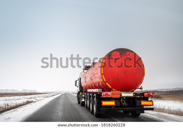 Oil tanker truck with red tank truck drives on\
winter highway