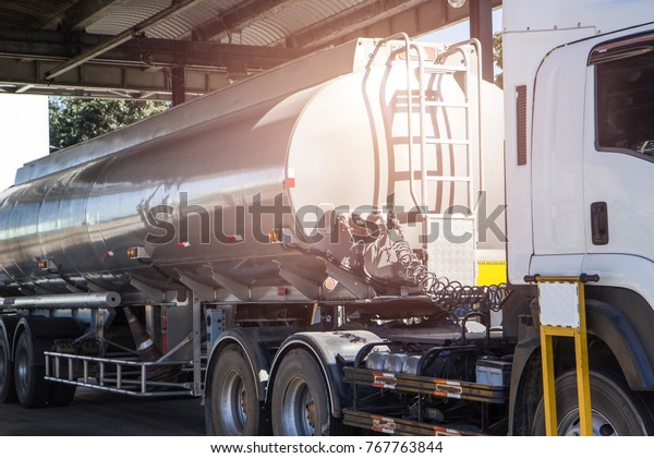 Oil truck releasing fuel oil stainless tanks in\
petrol station.