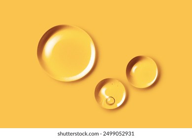 Oil vitamin C serum drops. Liquid droplets on yellow background. Cosmetic product with bubbles closeup