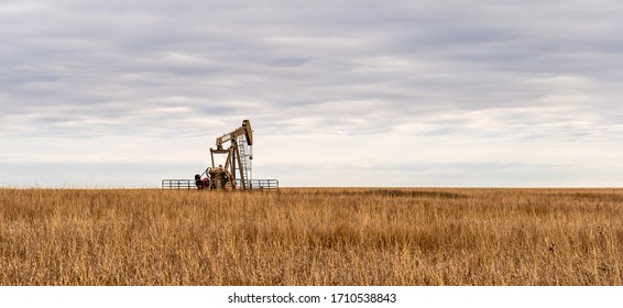 Oil Well Pump Jack Pumping Crude Oil For Fossil Fuel Energy. American Petroleum Oil And Gas Industry Equipment Extracting From A Prairie In The United States Of America.