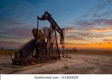 Oil Well, Pump Jack, In The San Joaquin Valley Of Central California At Sunset. Oil Industry Background. 