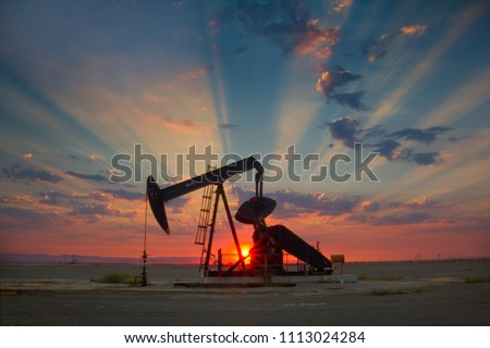 Oil well, pump jack, in the San Joaquin Valley of Central California at sunset. Oil industry background. 