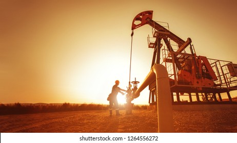 Oil Worker Is Checking The Pump Near Oil Derrick On The Sunset Background.