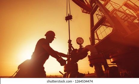 Oil worker is checking the oil pump on the sunset background.