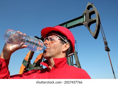 Oil Worker Drinking Clean Water From Plastic Bottle At Oil Well In The Hot Desert