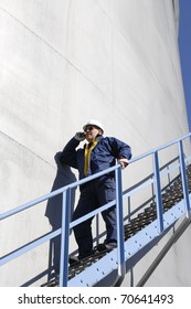 Oil Worker, Engineer Standing On Stairs Alongside Fuel Storage Tower,