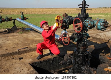 Oil Worker. Oil And Gas Industry.  Worker In Action At Pump Jack Oil Well. 