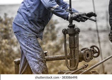 Oil Workers Check Oil Pump. Roustabouts Doing Dirty And Dangerous Work On An Oil Well Servicing Rig.