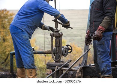 Oil Workers Check Oil Pump. Roustabouts Doing Dirty And Dangerous Work On An Oil Well Servicing Rig.