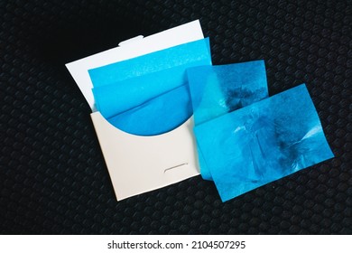 Oil-absorbing sheets or face wipes to remove excess oil on oily face. Pack of blue blotting paper on black background