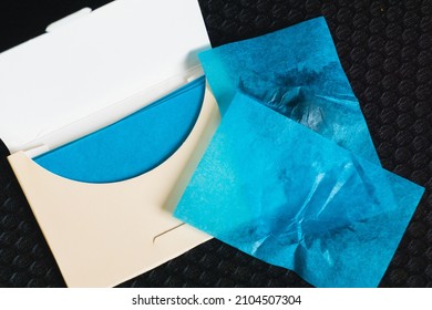 Oil-absorbing sheets or face wipes to remove excess oil on oily face. Pack of blue blotting paper on black background