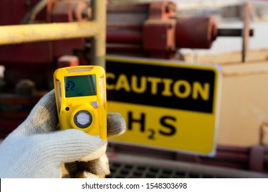 Oilfield technician checking H2S gas with his pocket type H2S Gas detector at well head in oilfield 
