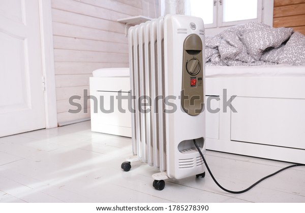 Oil-filled\
electrical mobile radiator heater for home heating and comfort\
control in the room in a wooden country\
house.