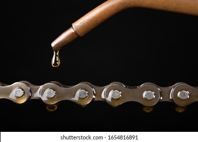 Oiling the bicycle chain with an oiler. Care of the bicycle's drive system. Dark background. - Powered by Shutterstock