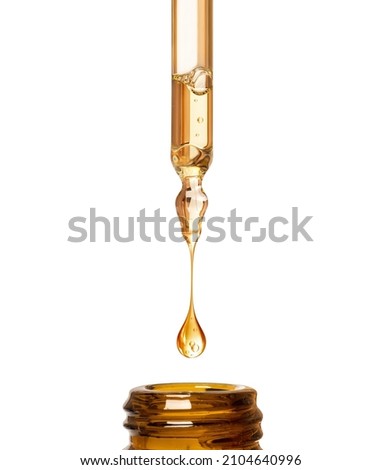 Oily drop dripping from pipette into cosmetic bottle close up, isolated on white background